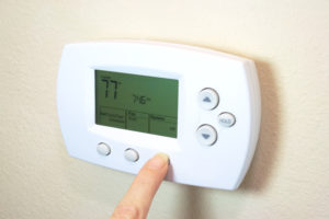 Female hand setting a digital thermostat